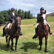 Two women riding horses in a green field at Reigning Downs Hauora Centre.